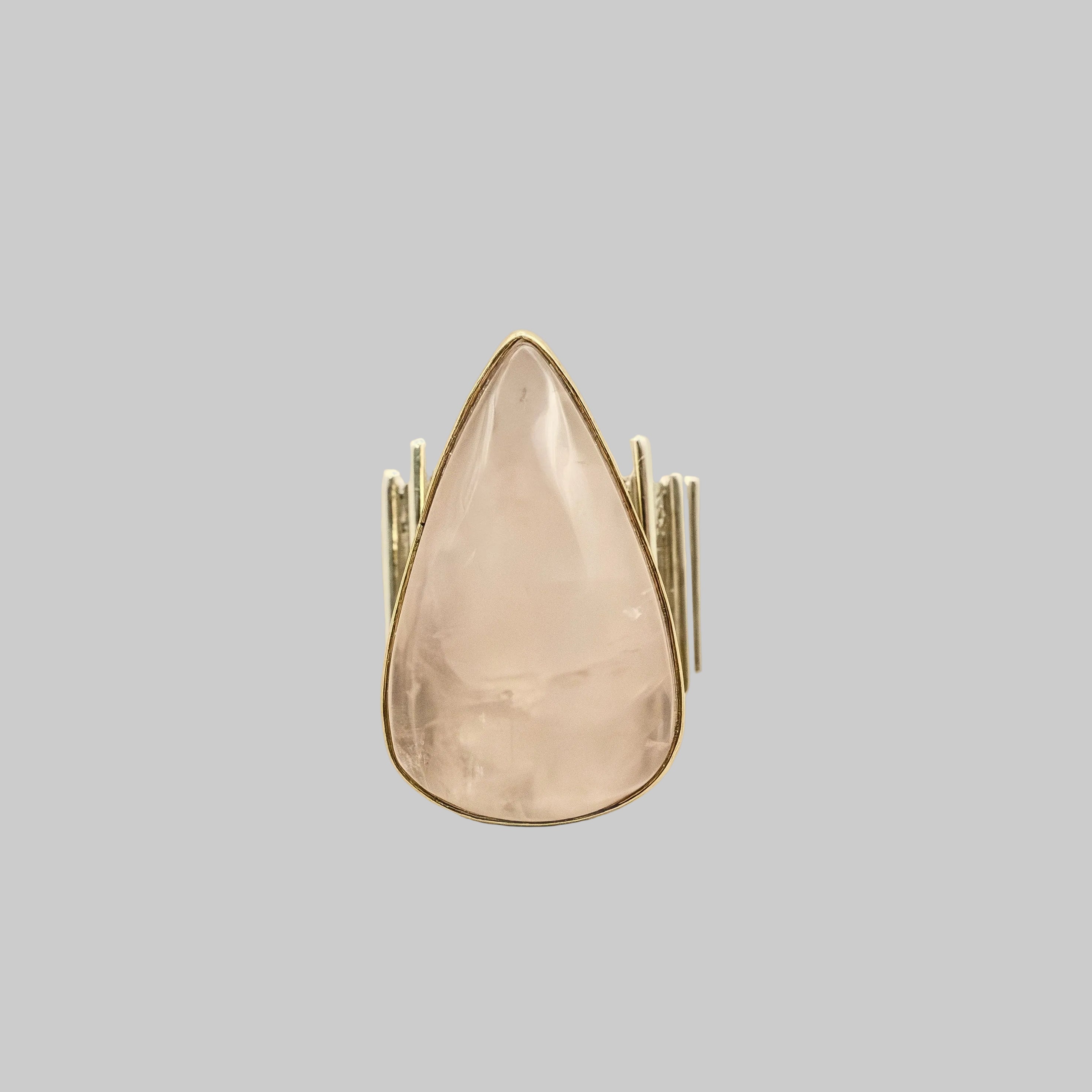 Teardrop-shaped ring with gold band on a beige background
