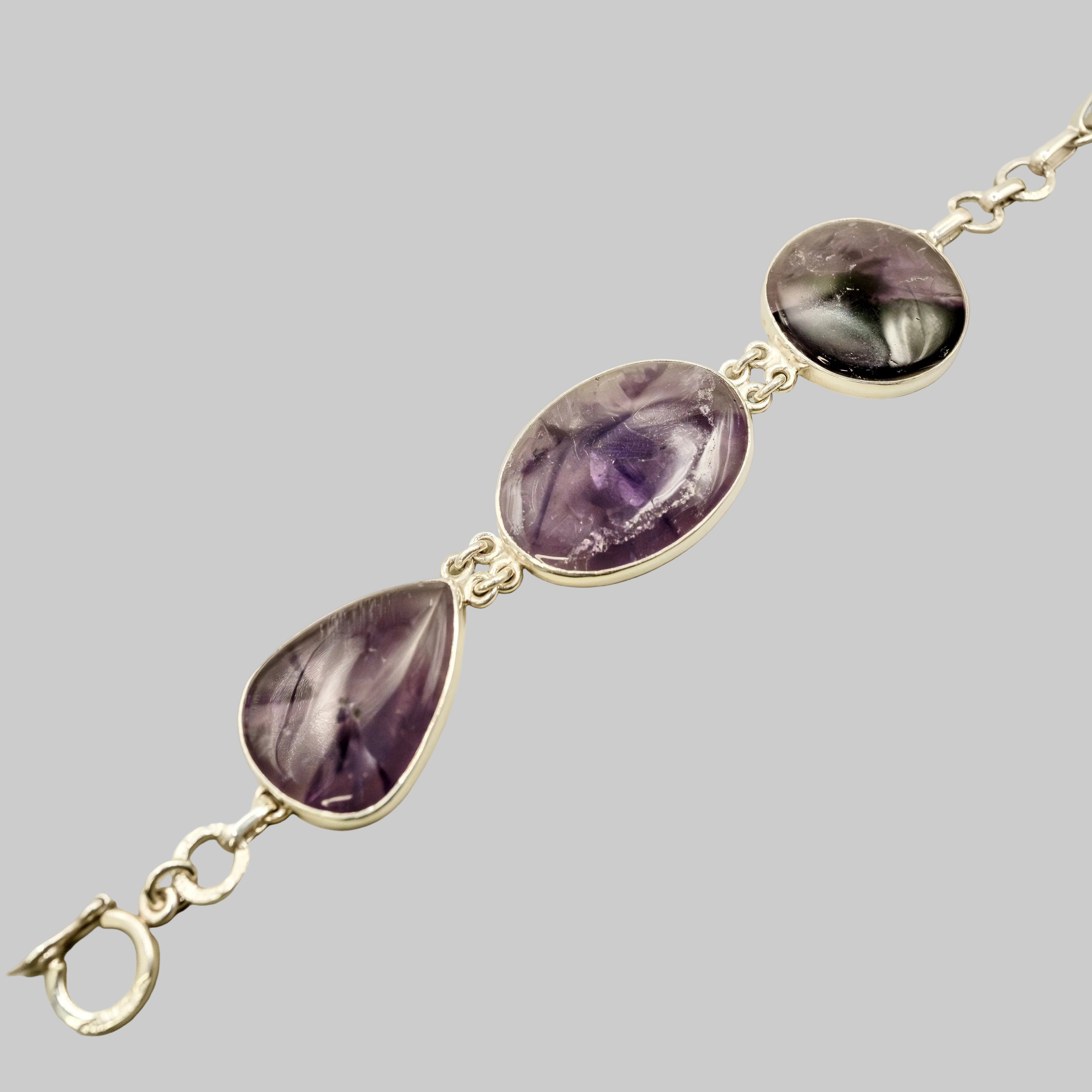 Bracelet with purple teardrop-shaped stones on a beige background