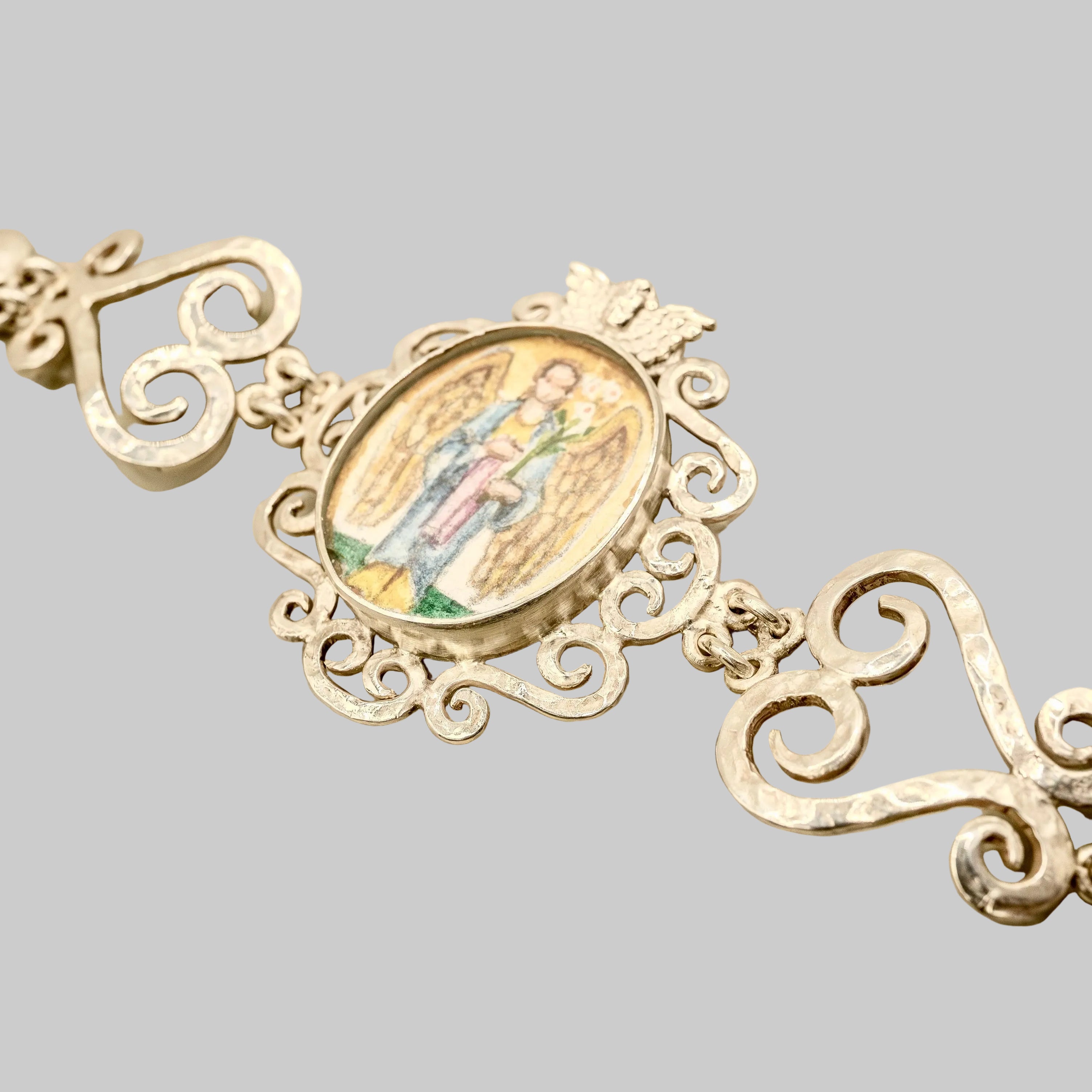 Silver pendant with intricate designs on a beige background