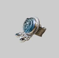 Silver ring with a blue stone and small silver pendants on a light gray background
