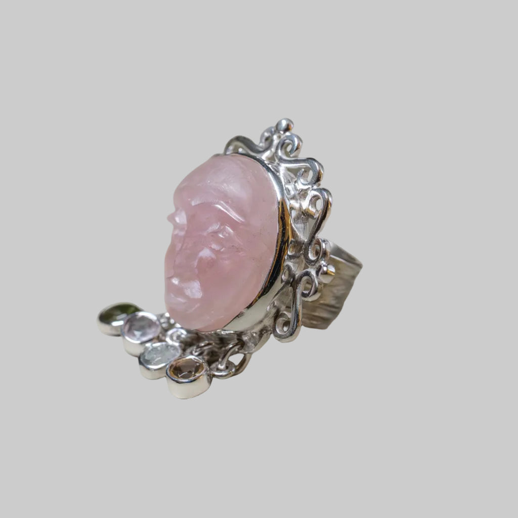 Silver ring with a pink stone on a beige background
