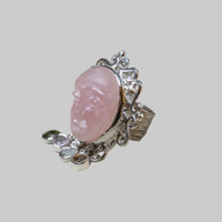 Silver ring with a pink stone on a beige background