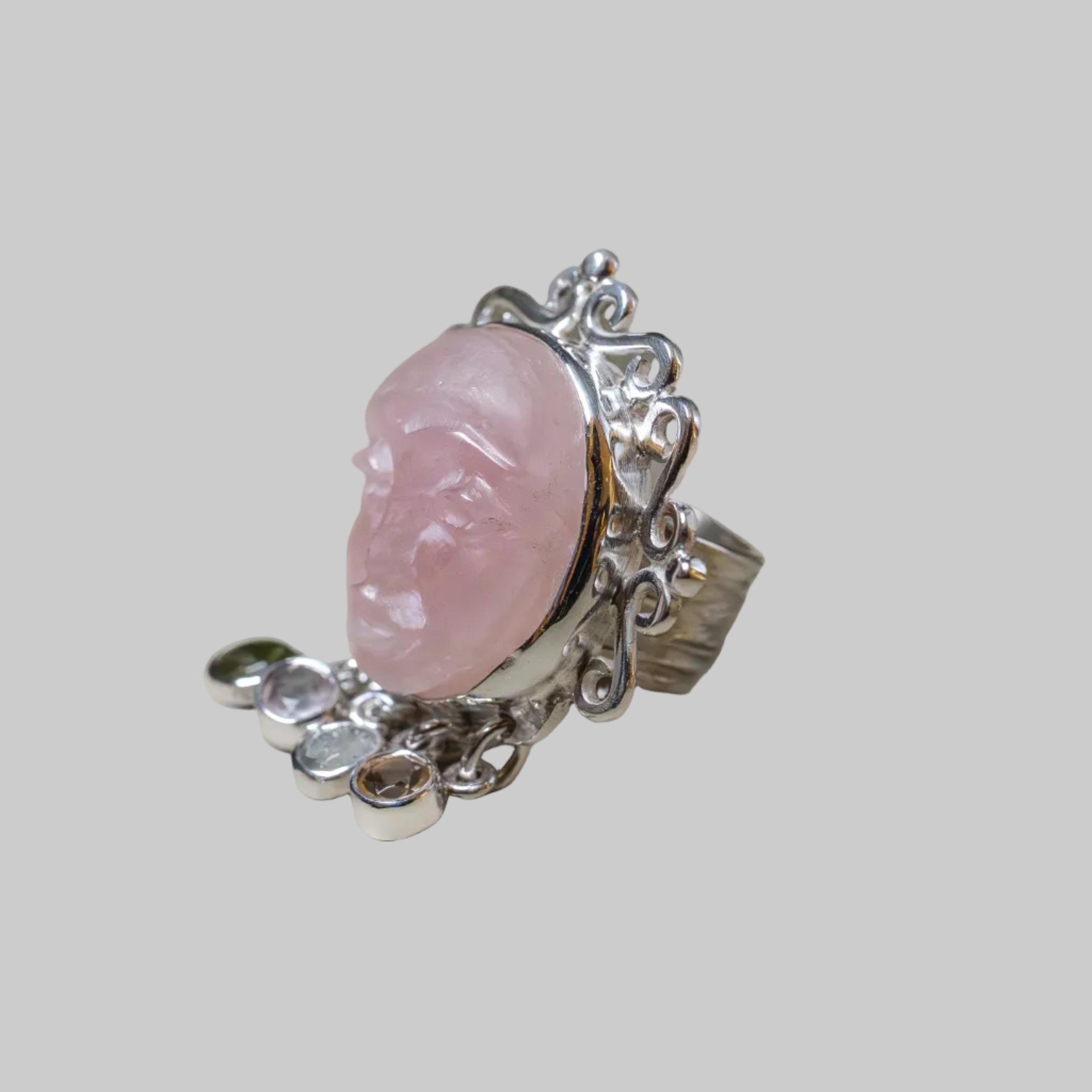 Silver ring with a pink stone on a beige background