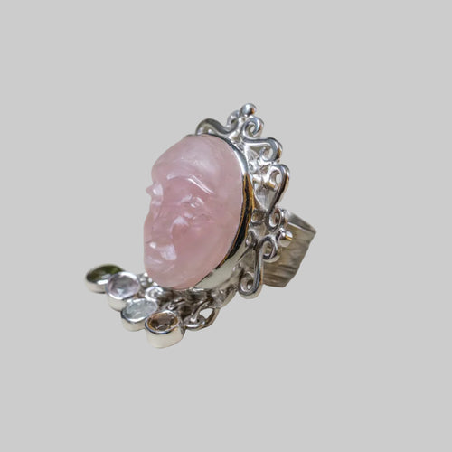 Silver ring with a pink stone on a beige background