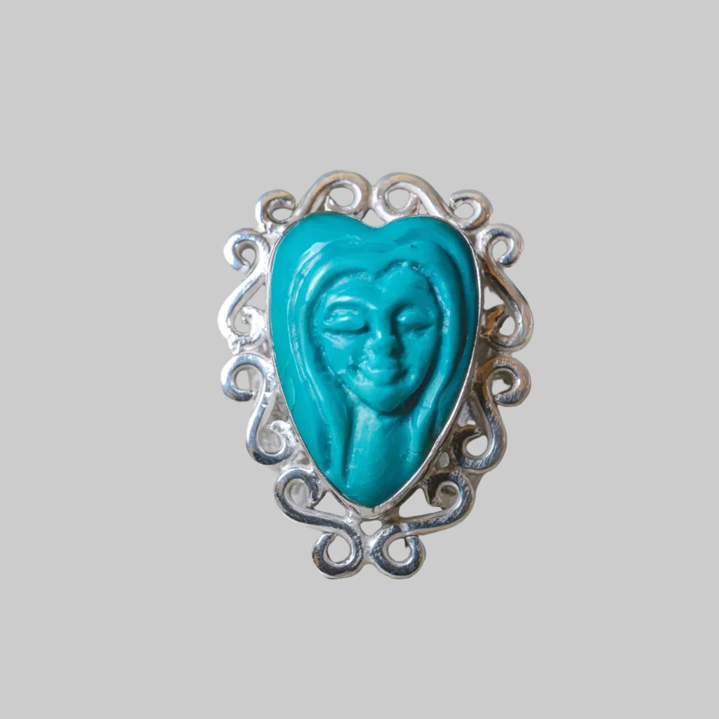 Turquoise heart-shaped ring with silver decorative band on a beige background