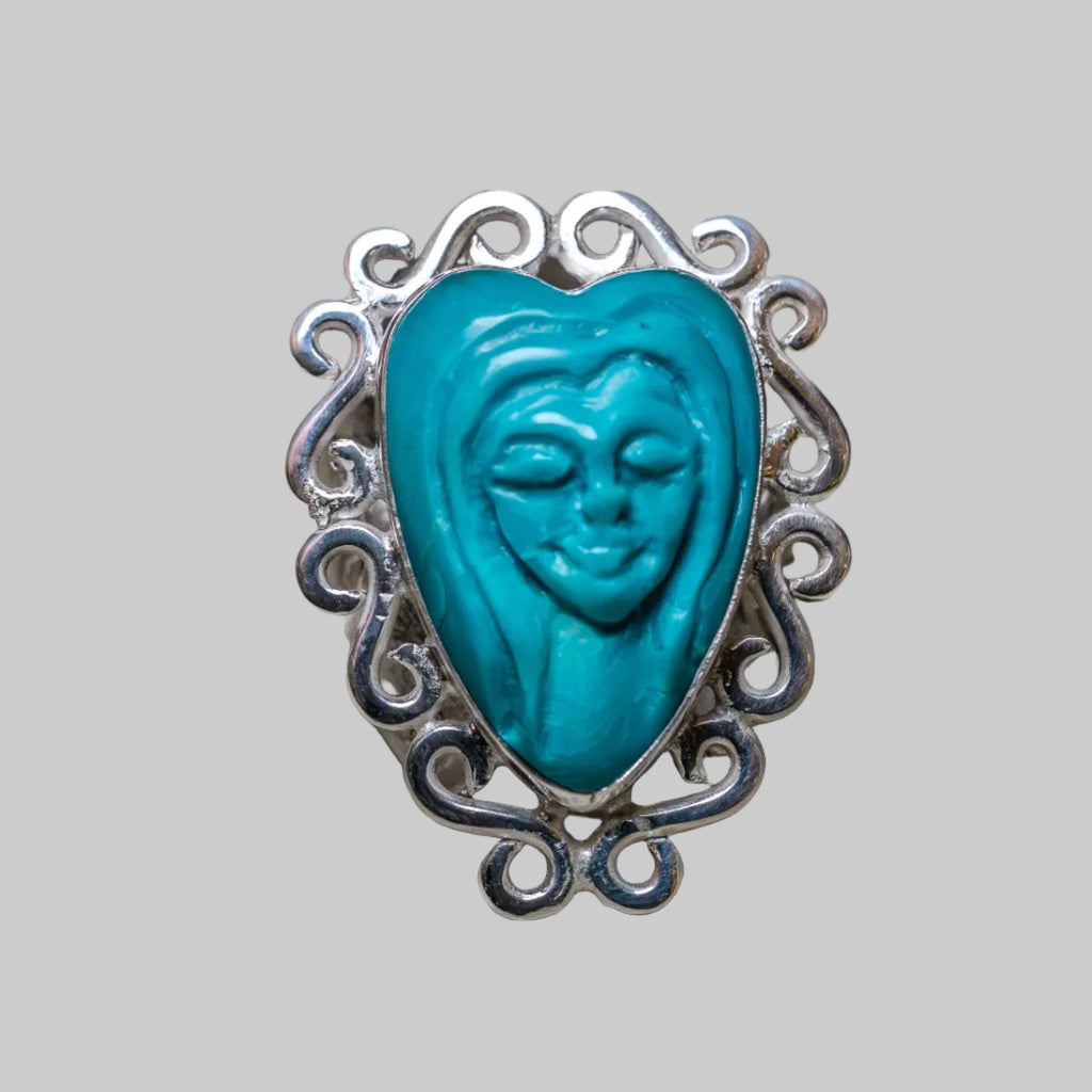Turquoise heart-shaped face ring with silver frame on a neutral background