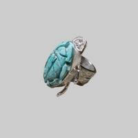Silver ring with a large turquoise stone on a light gray background