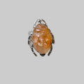 Ring with orange stone and silver band on a light gray background