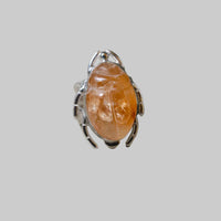 Ring with orange stone and silver band on a light gray background