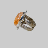 Silver ring with an orange stone on a neutral background