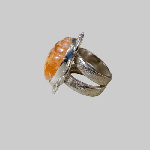 Silver ring with an orange stone on a neutral background