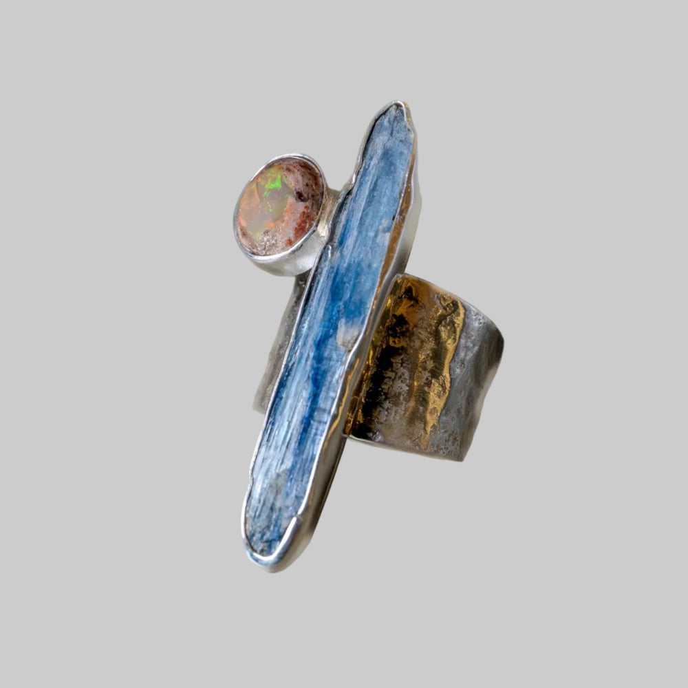 Silver ring with a large blue stone and smaller round stone on a light gray background