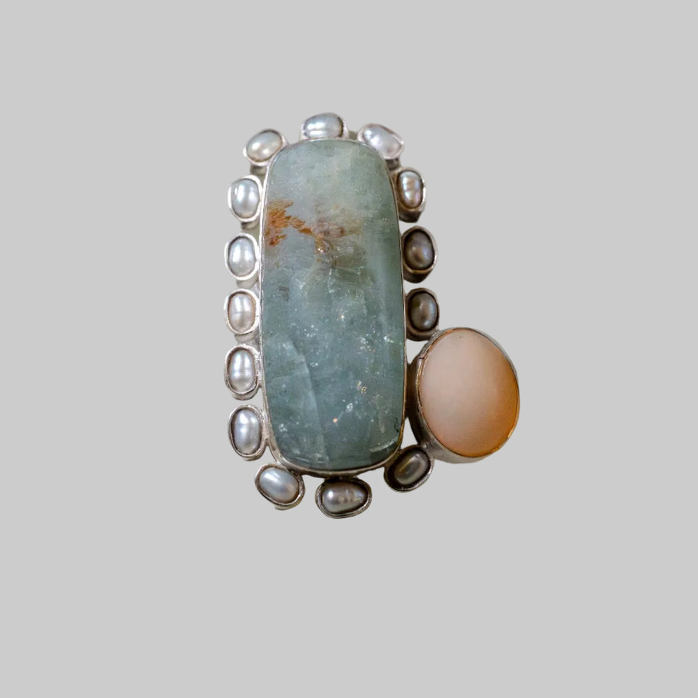 Ring with a large green stone and smaller stones on a beige background