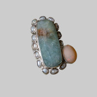 Ring with a large central stone and smaller stones on a beige background