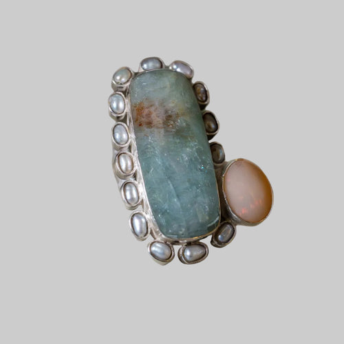 Ring with a large central stone and smaller stones on a beige background