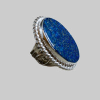 Silver ring with a blue stone on a light gray background