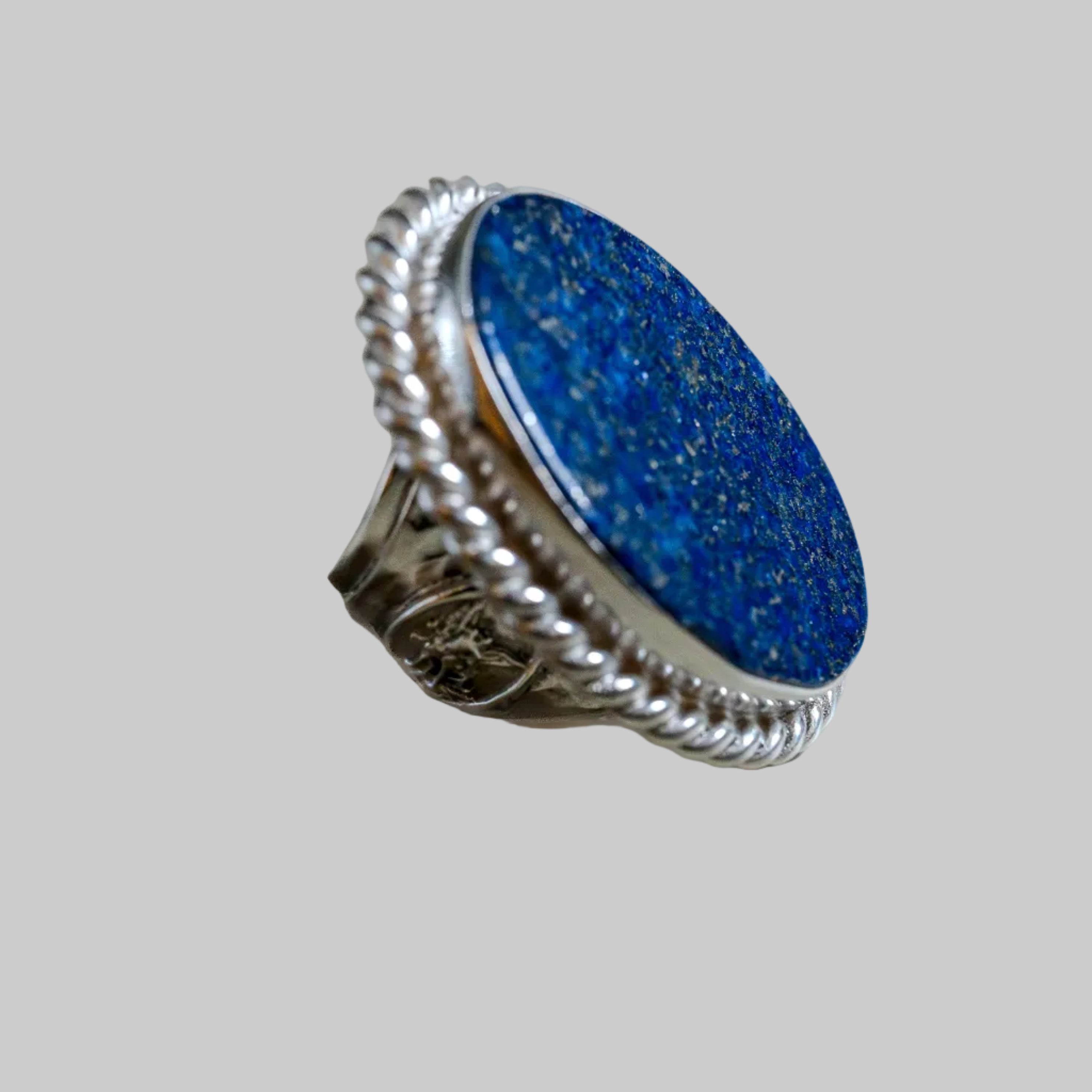 Silver ring with a blue stone on a light gray background