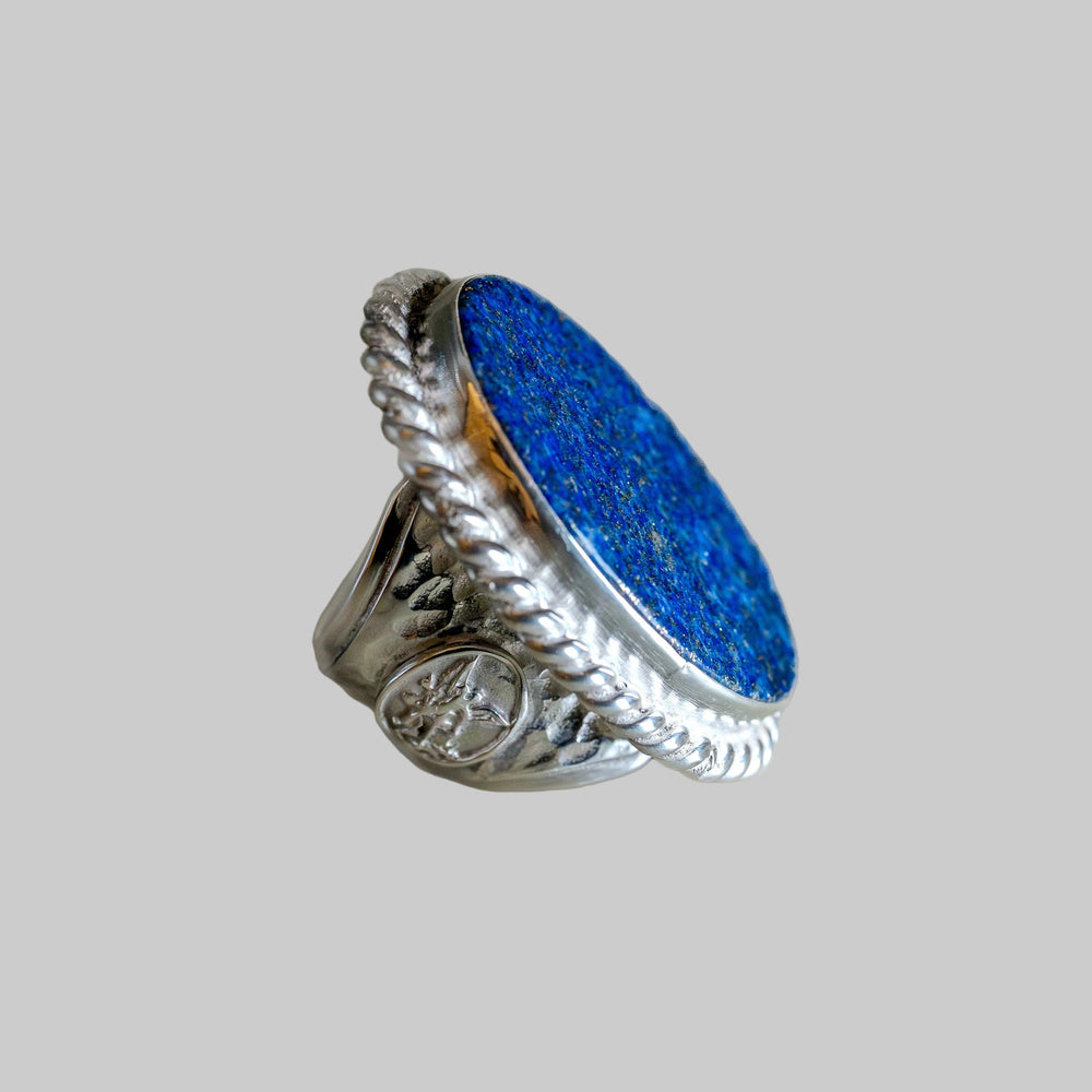 Silver ring with blue stone on a gray background