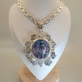 Necklace with a purple stone pendant on a white mannequin bust against a beige background