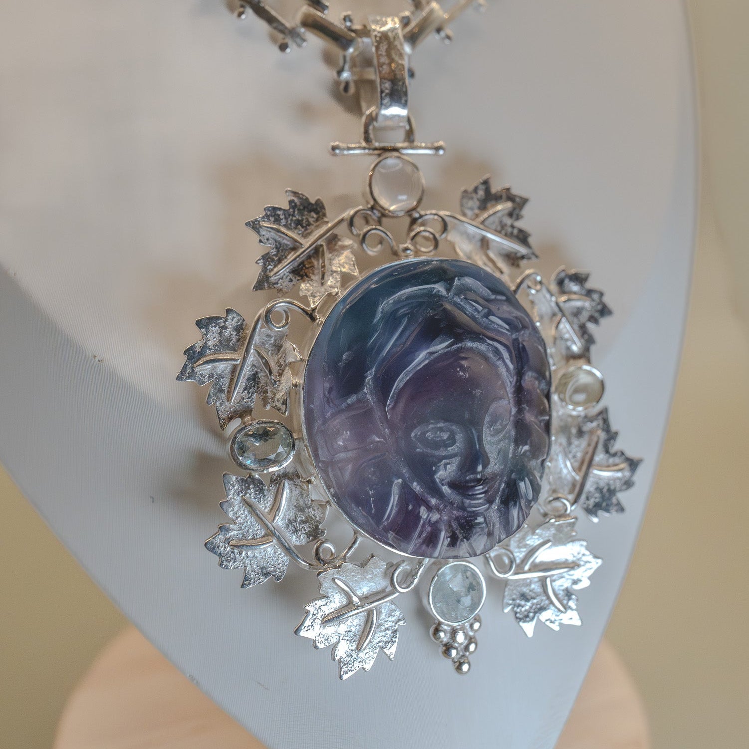 Silver necklace with a purple pendant on a white stand