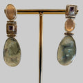 Pair of earrings with gemstones on a stand against a neutral background