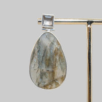 Jewelry earring with stone and silver frame on a neutral background