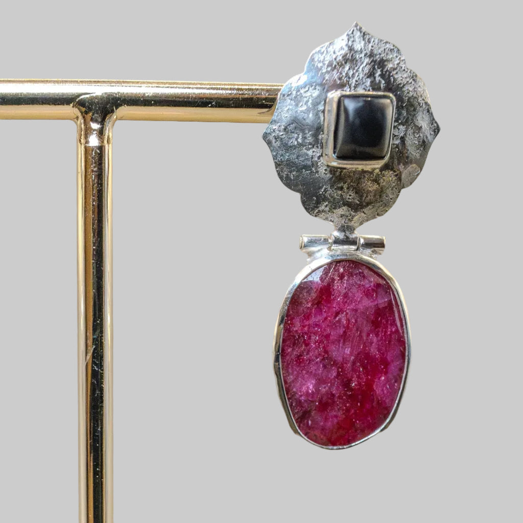 Jewelry with a pink stone and black gemstone on a beige background