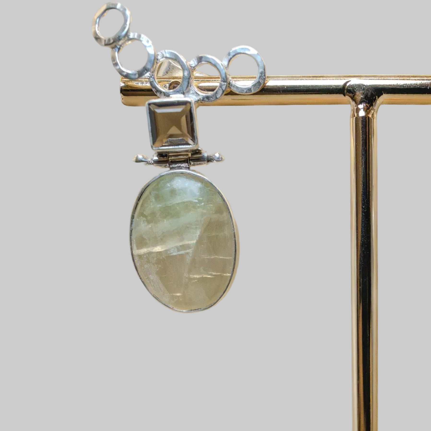 Silver pendant with a green stone on a beige background