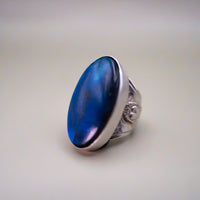Silver ring with a blue stone on a light gray background