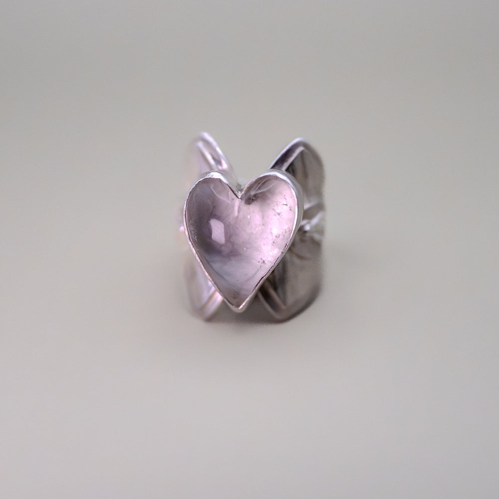 Silver heart-shaped ring on a light gray background
