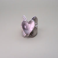 Silver heart-shaped ring on a light gray background
