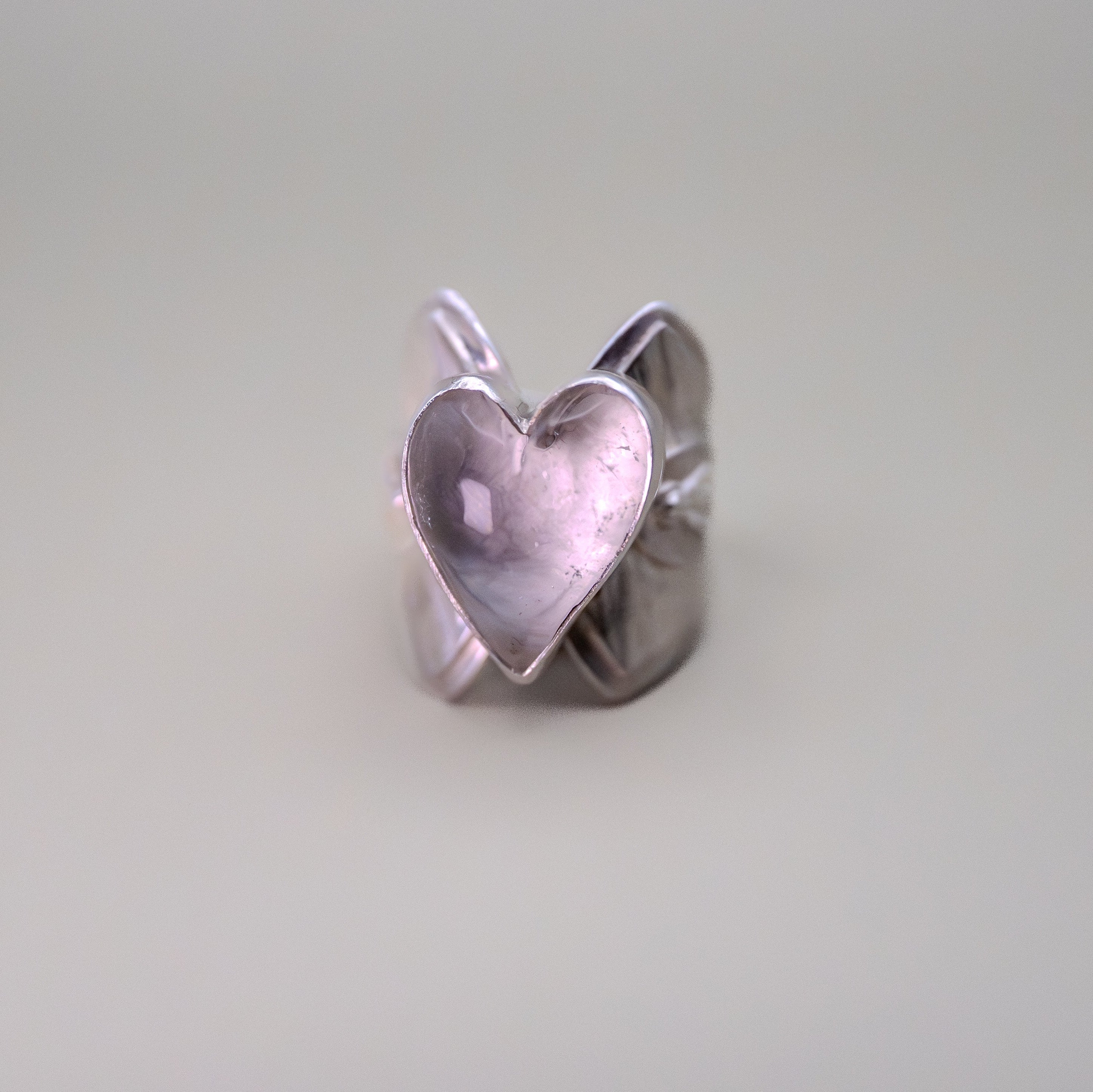 Silver heart-shaped ring on a light gray background