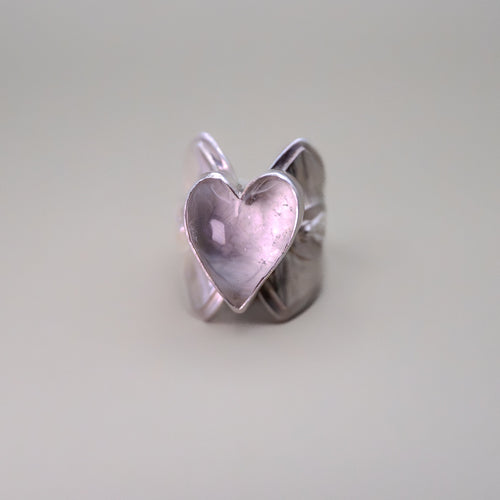 Silver heart-shaped ring on a light gray background