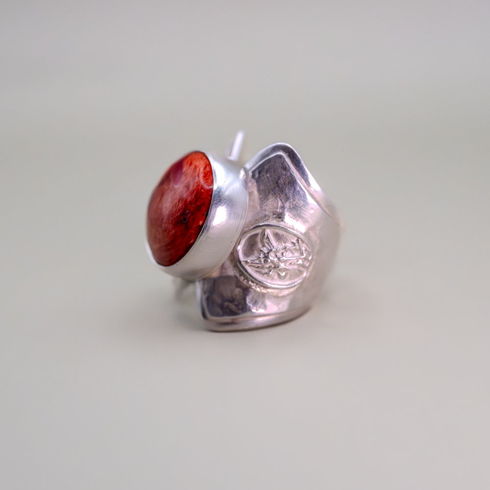 Silver ring with a red stone on a light gray background