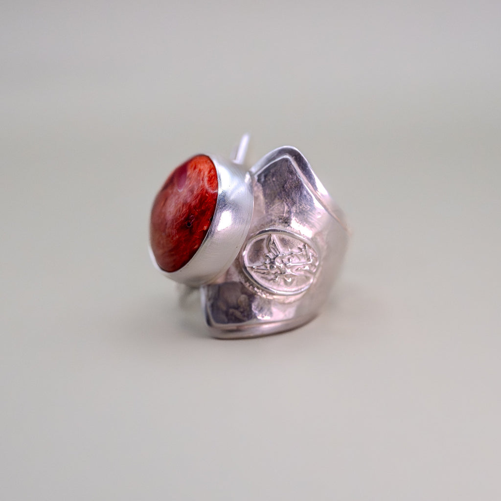 Silver ring with a red stone on a light gray background
