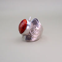 Silver ring with a red stone on a light gray background