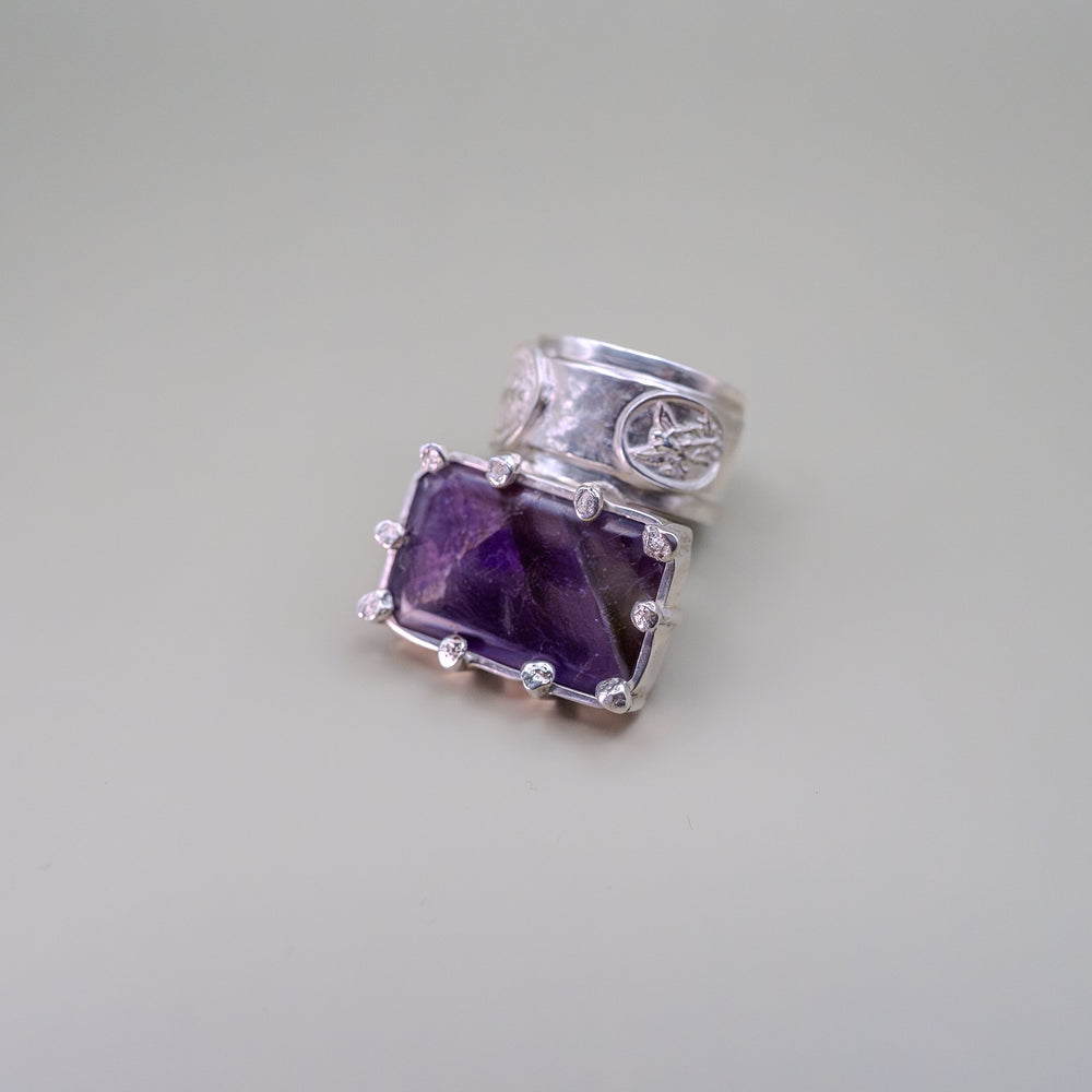 Silver ring with a purple gemstone on a light gray background