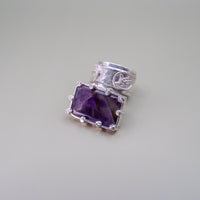 Silver ring with a purple gemstone on a light gray background