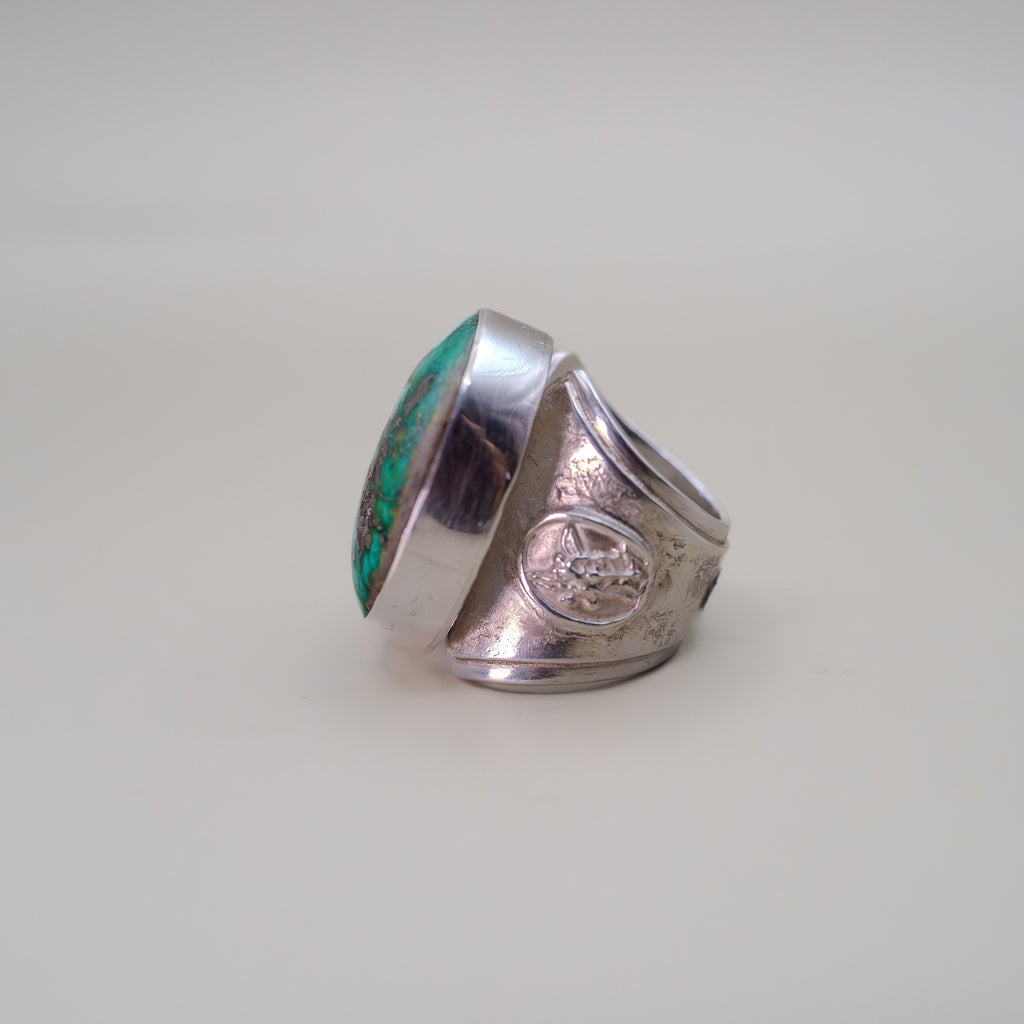 Silver ring with turquoise inlay on a light gray background