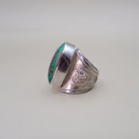 Silver ring with turquoise inlay on a light gray background