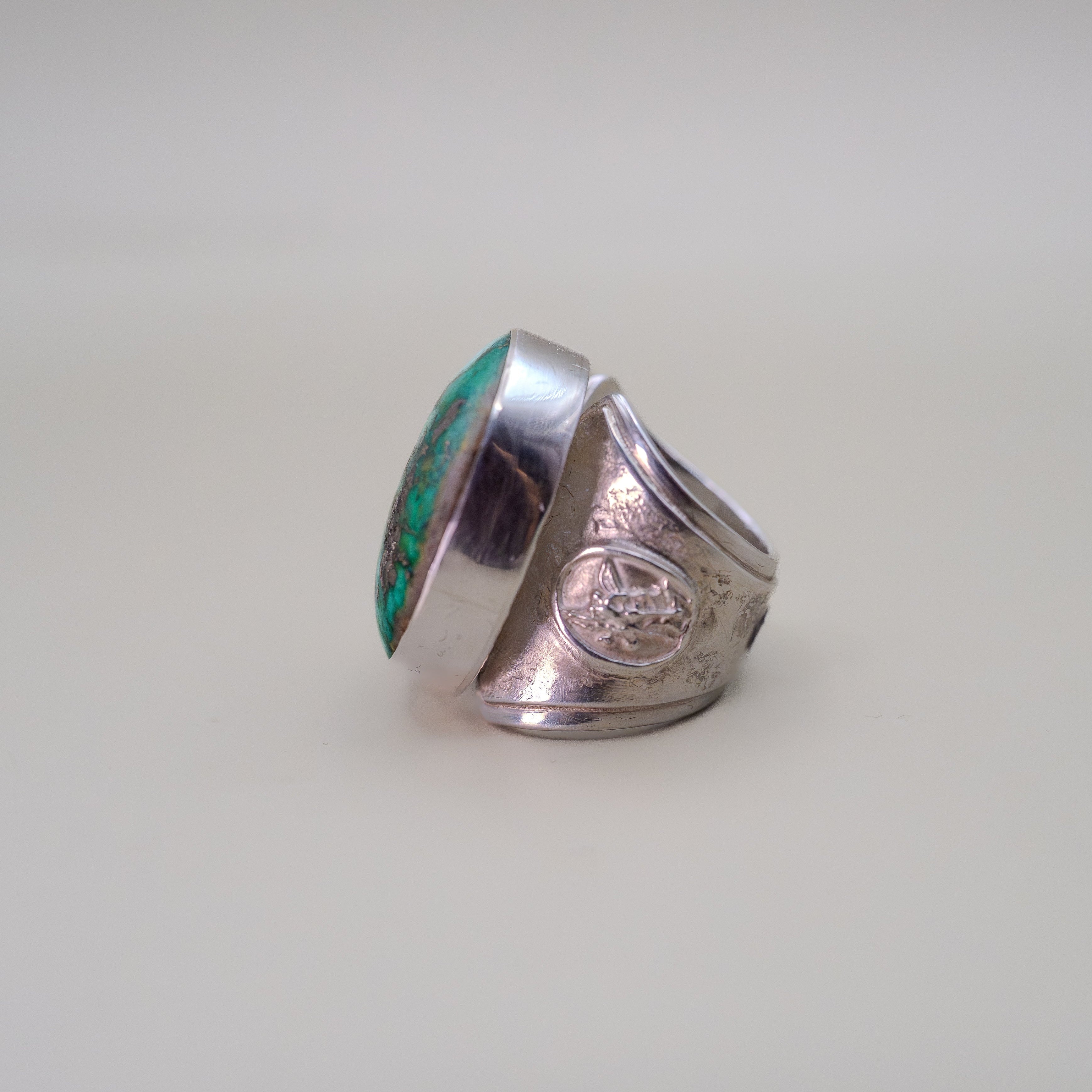 Silver ring with turquoise inlay on a light gray background