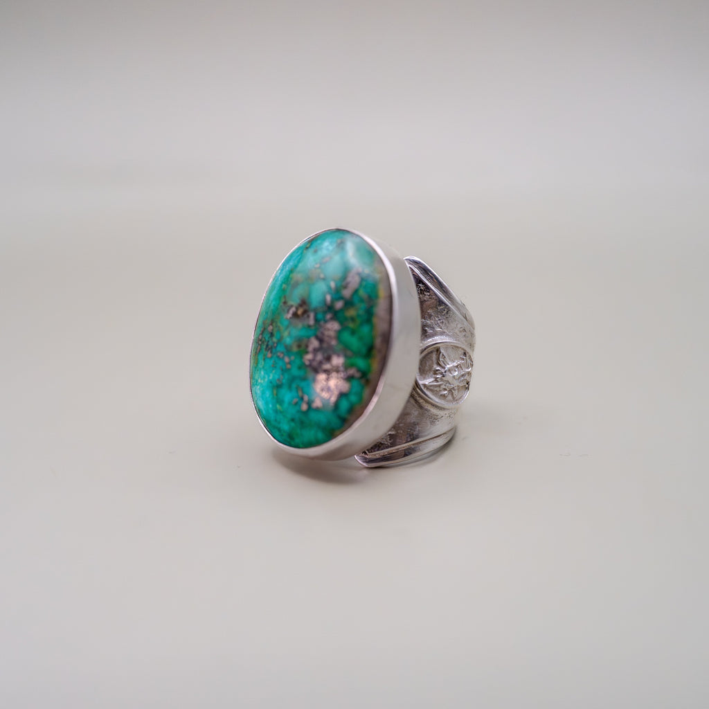 Silver ring with a large turquoise stone on a light gray background