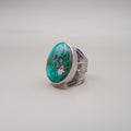 Silver ring with a large turquoise stone on a light gray background