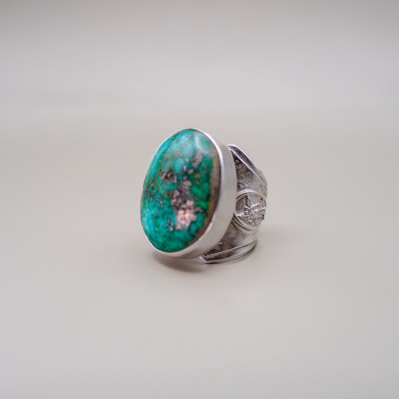 Silver ring with a large turquoise stone on a light gray background