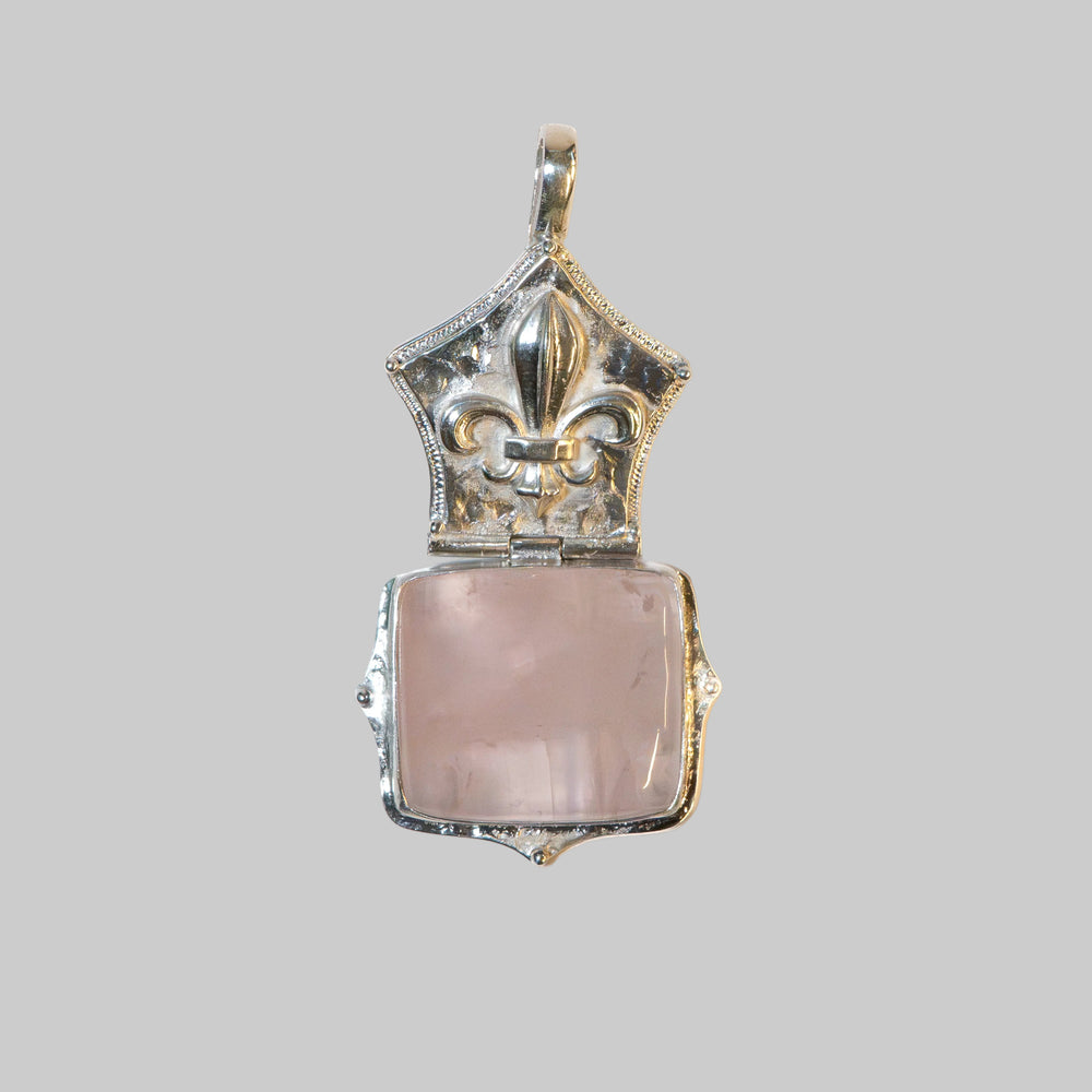 A vintage-style silver locket pendant with a rose quartz heart-shaped stone, shown open against a plain white background.