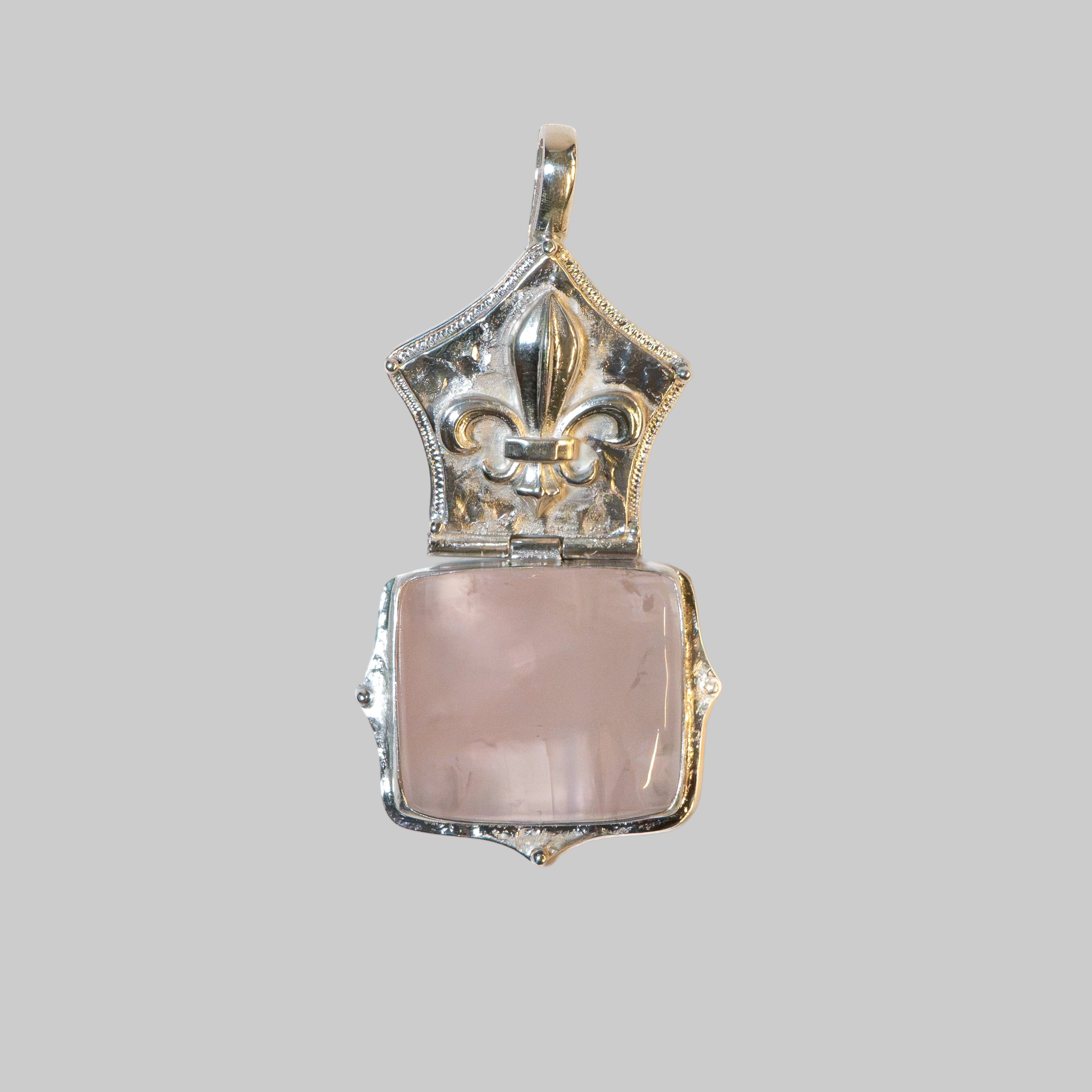 A vintage-style silver locket pendant with a rose quartz heart-shaped stone, shown open against a plain white background.