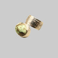 Silver ring with a green stone on a light beige background